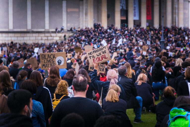 A large crowd gathered at a Black Lives Matter protest holding various signs advocating for equality.